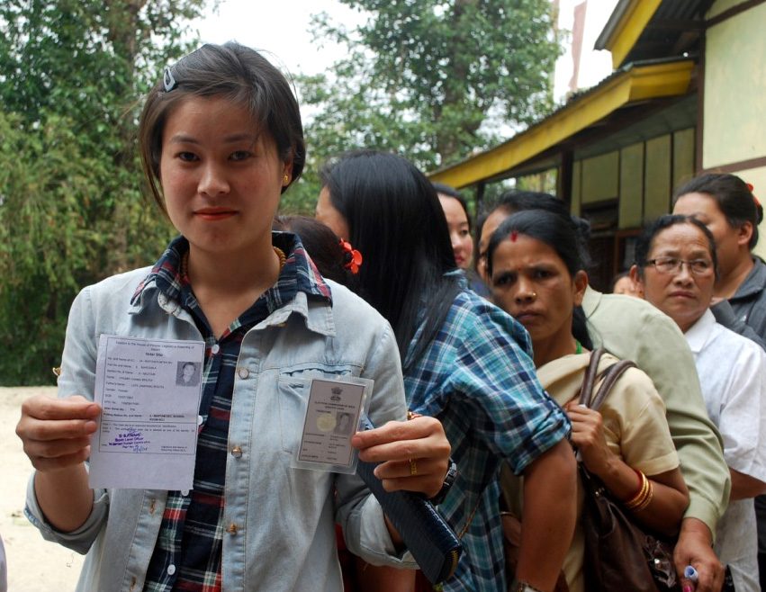 A young voter holding up her identity card and voter slip
